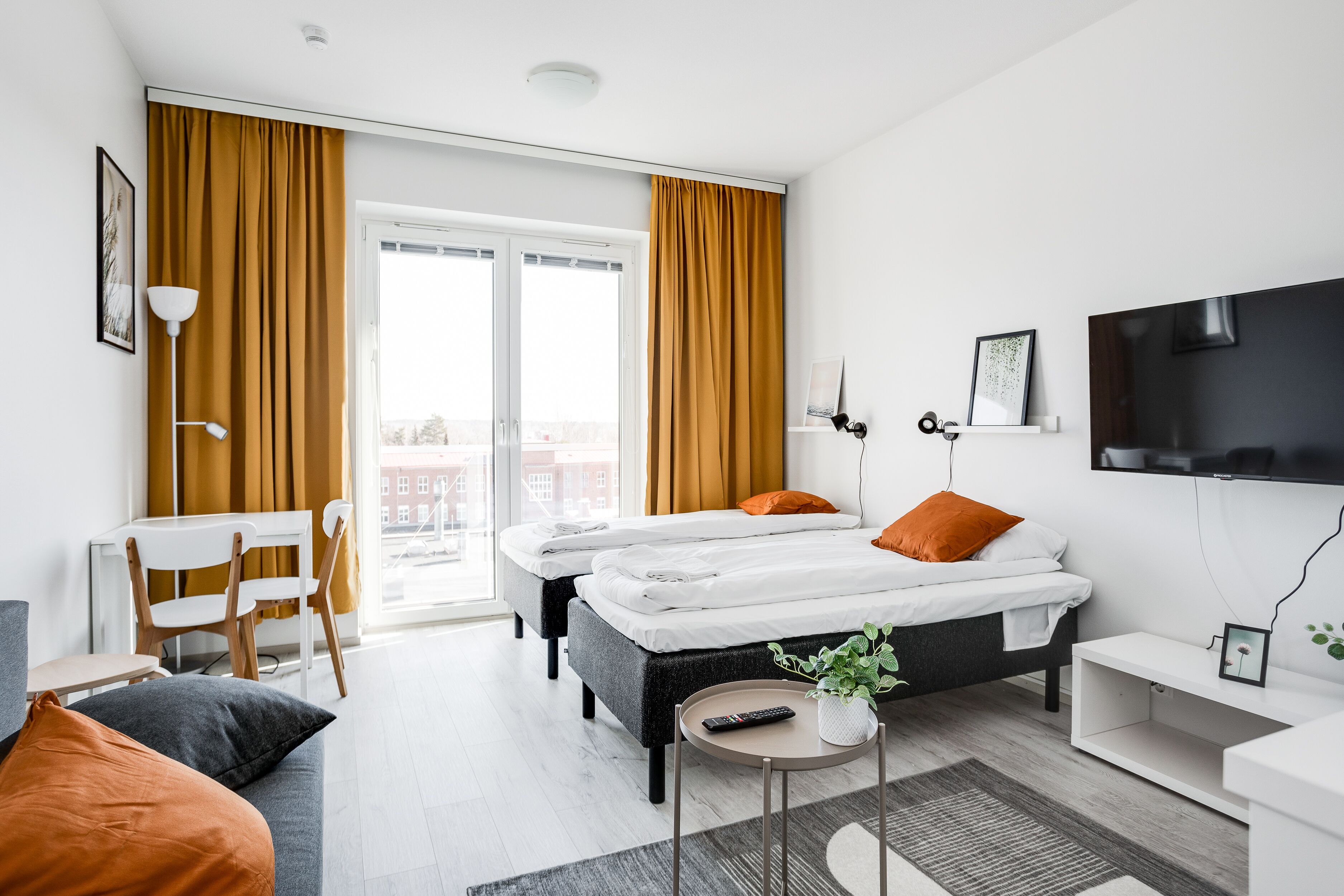 Moderni hotellihuone, jossa on suuri sänky, kaksi yöpöytää, työpöytä ja televisio.