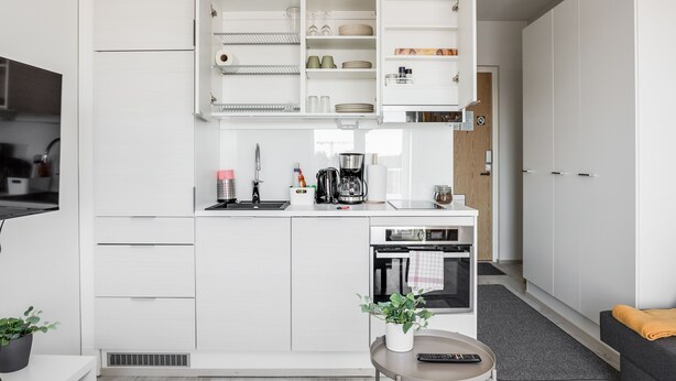 A modern kitchen with white cabinetry, a built-in oven, and a coffee maker. - Hiisi Homes Nokia (Nokia)