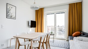 A modern living room with a dining area, a sofa, and a TV on the wall. - Hiisi Homes Nokia (Nokia)