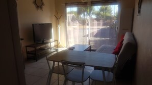Un salon avec un téléviseur posé sur un meuble, une table à manger avec des chaises et un canapé.