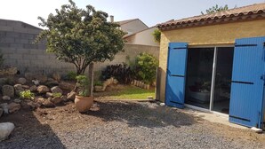 Une maison avec une allée en gravier, un pot de fleurs et une porte bleue.