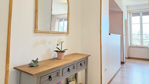 A hallway with a wooden console table, a mirror, and a potted plant.