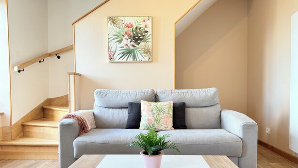 A modern living room with a grey sofa, a white coffee table, and a potted plant.