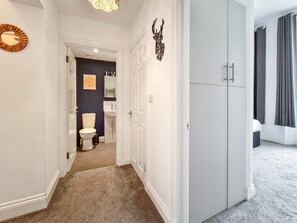A hallway leading to a bathroom with a toilet, sink, and vanity. There is a wardrobe with a mirror and a decorative deer head on the wall. - Margaret's Ground by Fortuna Property Portfolio, The Margaret's Ground (Cheltenham)