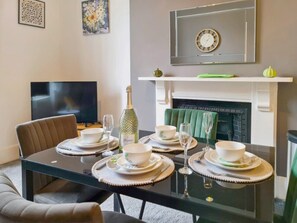 A dining area with a glass table set for four, a television, and a fireplace. - Margaret's Ground by Fortuna Property Portfolio, The Margaret's Ground (Cheltenham)