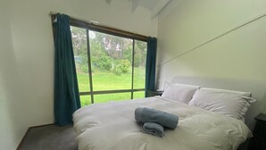 A bedroom with a large bed, a nightstand, and a window with curtains. - Idyllic Family Getaway on a farm  - Blue Mountain (Bowen Mountain)