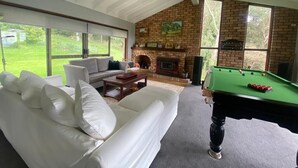 A spacious living room with a white sofa, a billiards table, and a fireplace. - Idyllic Family Getaway on a farm  - Blue Mountain (Bowen Mountain)
