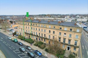 A multi-story building with a row of windows, a parking lot, and a street in the foreground. - Margaret's Garden by Fortuna Property Portfolio, The Margaret's Garden (Cheltenham)