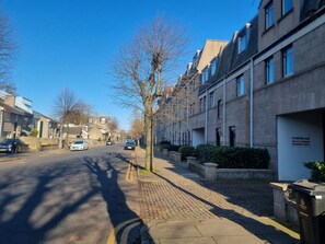 A residential street with terraced houses, a clear sky, and a trash bin labeled "General Waste".