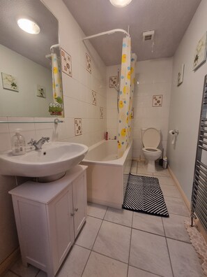 A bathroom with a sink, bathtub, toilet, and shower curtain.