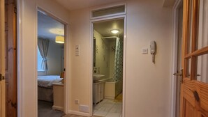 A hallway with a skylight, a red and white patterned rug, and a wooden door on the right.