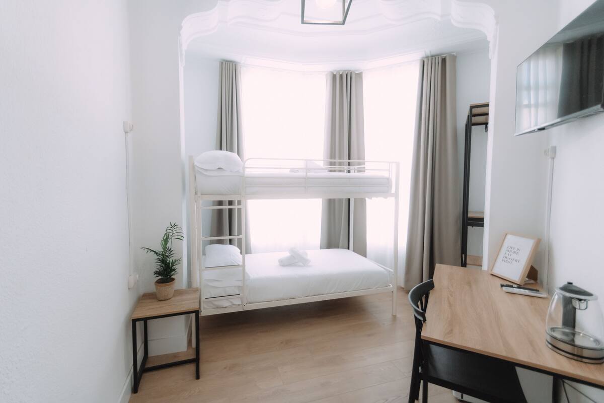 A bunk bed room with a desk, a potted plant, and a framed quote on the wall.