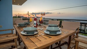 A wooden dining table set with blue bowls, plates, and cutlery, overlooking a scenic view.