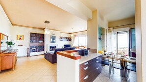 A modern kitchen with a dining area, a fireplace, and a large window.
