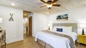 A bedroom with a wooden ceiling, a bed with white bedding, a nightstand with a lamp, and a painting on the wall. - No steps, Game Room, Canoe & Kayaks, Dock, All Paved Roads! 10 min to 2 marinas! (Jasper)