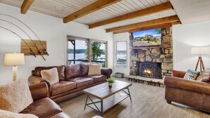 A cozy living room with a stone fireplace, leather sofas, wooden beams, and a view of the outdoors. - No steps, Game Room, Canoe & Kayaks, Dock, All Paved Roads! 10 min to 2 marinas! (Jasper)