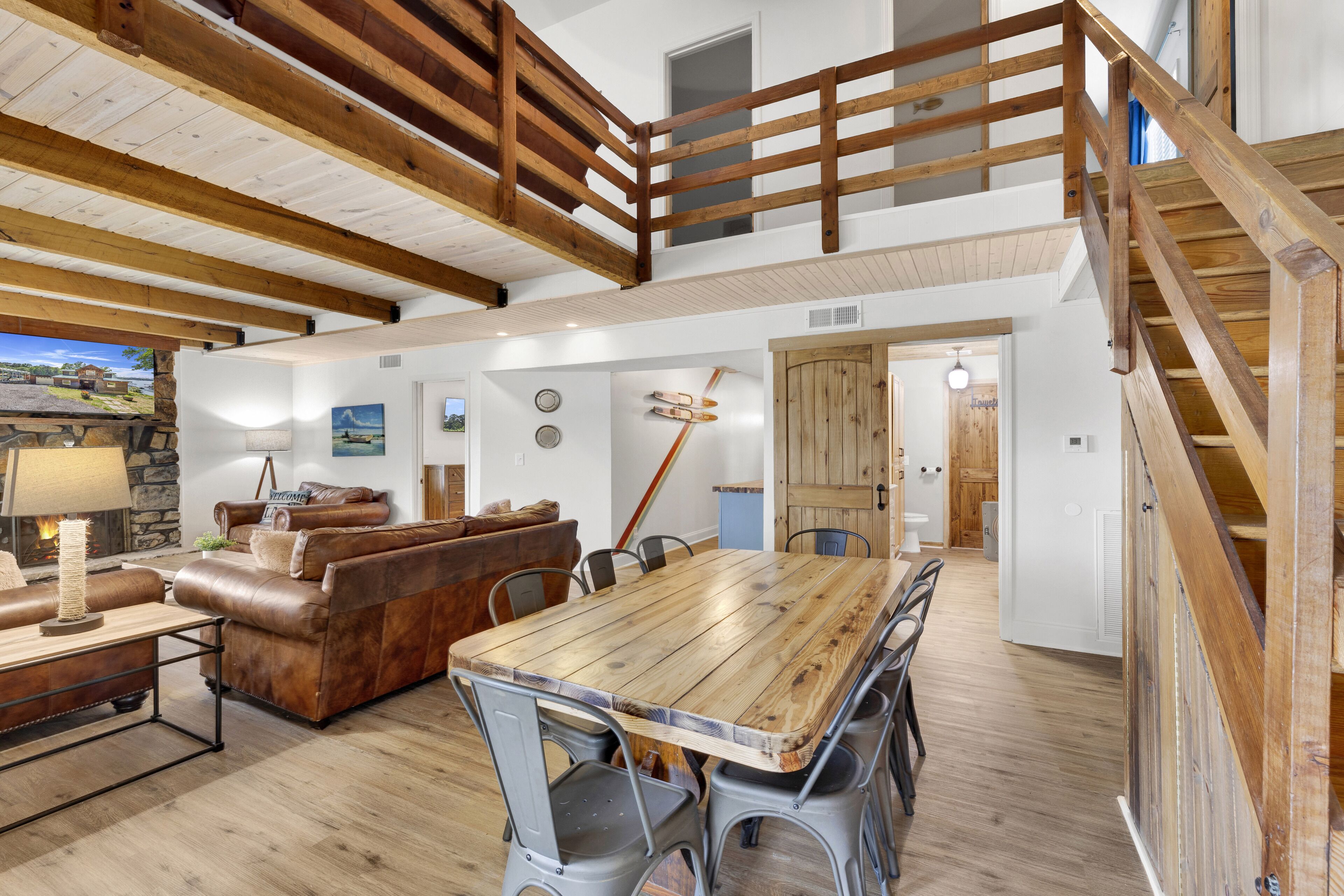 Un vaste espace de vie comprenant une table à manger en bois, un canapé en cuir et un haut plafond en bois avec des poutres apparentes.