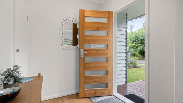A modern wooden door with glass panels, a white wall, and a small indoor plant. - Alpine View Cottage - Close to town (Bright)