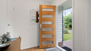 A modern wooden door with glass panels, a white wall, and a small indoor plant. - Alpine View Cottage - Close to town (Bright)