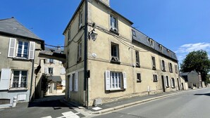 Un edificio de varios pisos con fachada color beige, contraventanas blancas y una señal que dice 