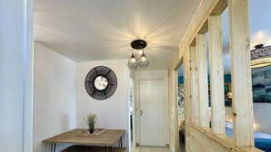 Un interior moderno con una mesa de comedor de madera, bancos, un elemento decorativo en la pared y vistas amplias a través de ventanas grandes.