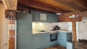 A kitchen with blue cabinets, a wooden ceiling, and a checkered floor.