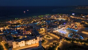 Vista aerea di un resort con diverse piscine, una grande piscina centrale e una zona spiaggia.