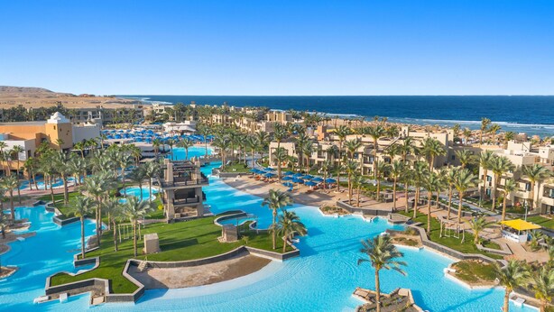 Un resort con diverse piscine, palme e vista sulla spiaggia.