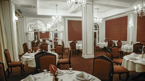 Un comedor elegante con varias mesas, sillas y candelabros.