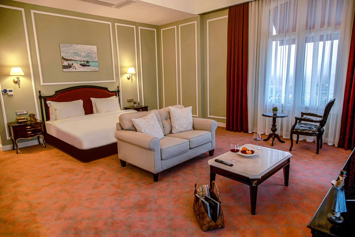 Una habitación de hotel con cama, sofá, mesa de comedor y una silla.