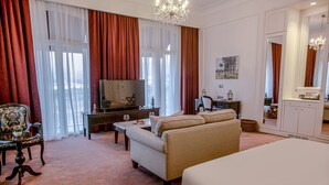 Habitación de hotel con sofá, televisión, mesa de comedor y una cama grande.