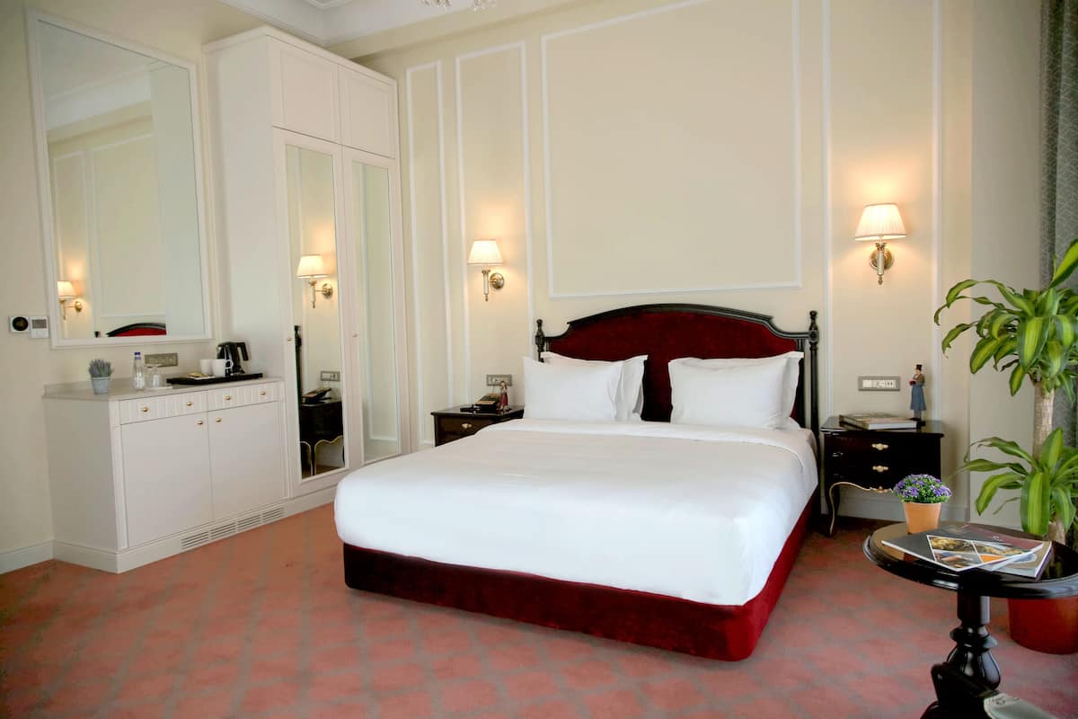Una habitación de hotel con una cama grande, un tocador, una mesita de noche y un espejo.