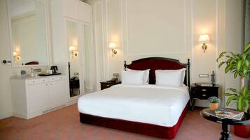 Una habitación de hotel con una cama grande, un tocador, una mesita de noche y un espejo.
