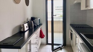 A modern kitchen with a black countertop, white cabinets, and a sliding glass door leading to a balcony. - "Le Côté port" Type 3 near the port - wifi - air conditioning - parking (LA CIOTAT)