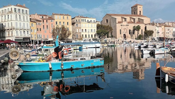 A marina with boats docked, a church with a bell tower, and colorful buildings along the waterfront. - "Le Côté port" Type 3 near the port - wifi - air conditioning - parking (LA CIOTAT)