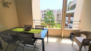 A balcony with a dining table, chairs, and a wicker chair. - "Le Côté port" Type 3 near the port - wifi - air conditioning - parking (LA CIOTAT)