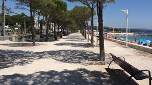 A seaside promenade with trees, benches, and a beach in the background. - "Le Côté port" Type 3 near the port - wifi - air conditioning - parking (LA CIOTAT)