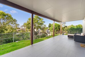 A covered patio area with a view of a green landscape and trees.