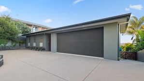 Een modern huis met twee verdiepingen, een garage, een oprit en een aangelegde tuin.