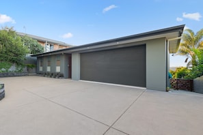 Uma casa moderna de dois andares com garagem, entrada por meio de um caminho e jardim bem cuidado.