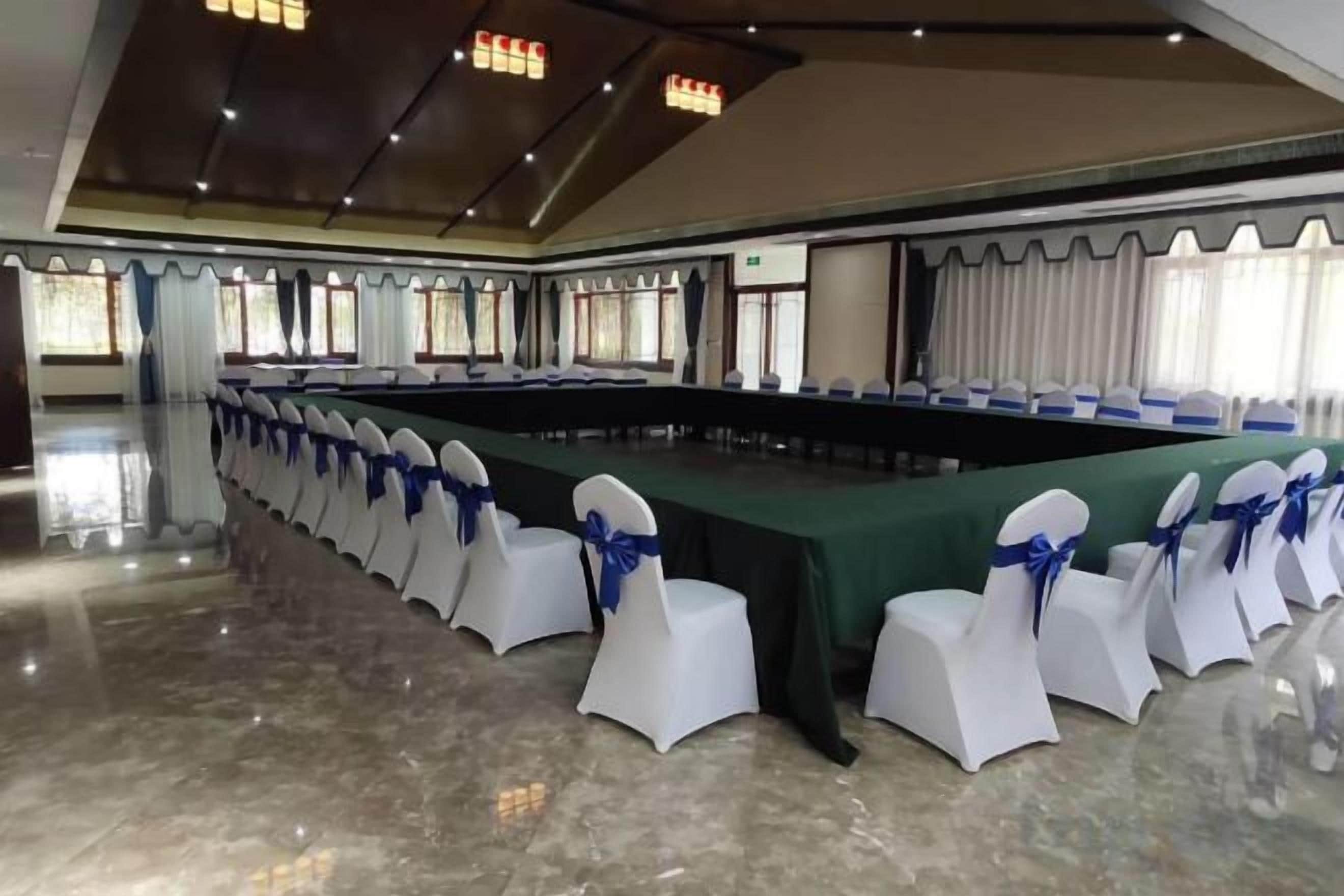 A conference room with a long table and chairs, a polished floor, and a high ceiling with lights.