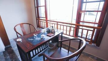 A dining area with a wooden table and chairs, a window with a view, and a small table with a teapot and cups.