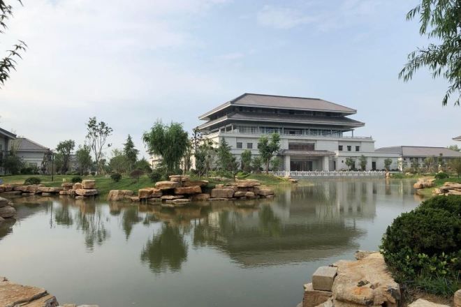 A building with a flat roof and a reflection in a calm body of water.