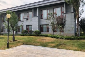A modern multi-story building with a flat roof, rectangular windows, and a paved courtyard. - Laozi Boxue International Hotel (Luyi)