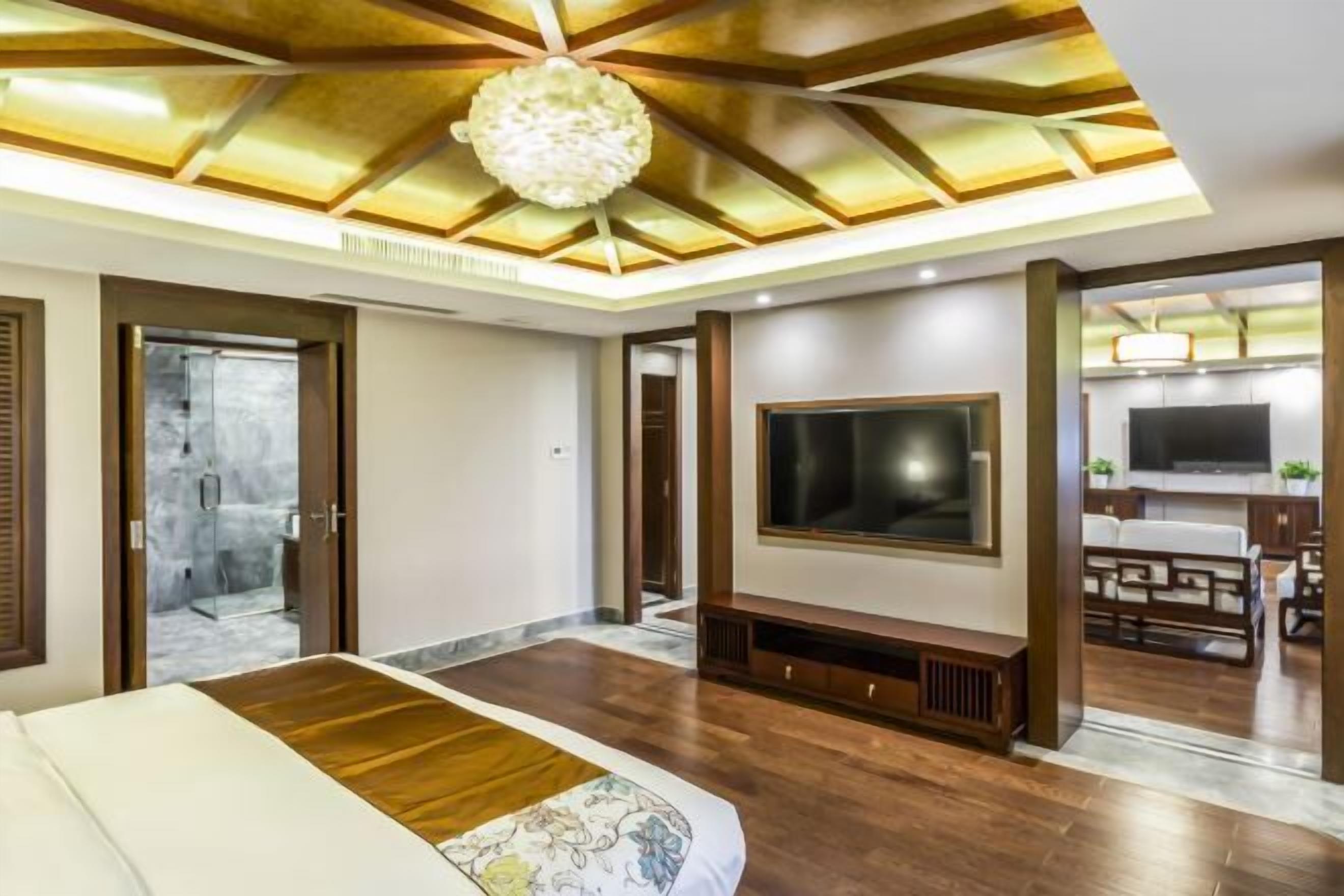 A modern hotel room with a large bed, a TV, and a wooden ceiling design.