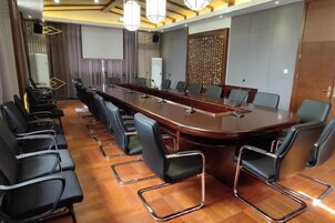 A conference room with a long table, chairs, and a projector screen.