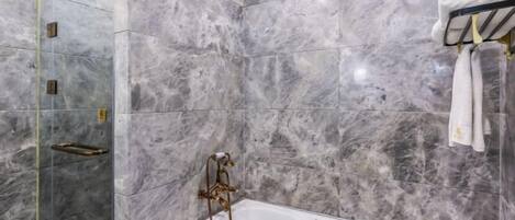 A bathroom with a freestanding bathtub, marble walls, and a towel rack.