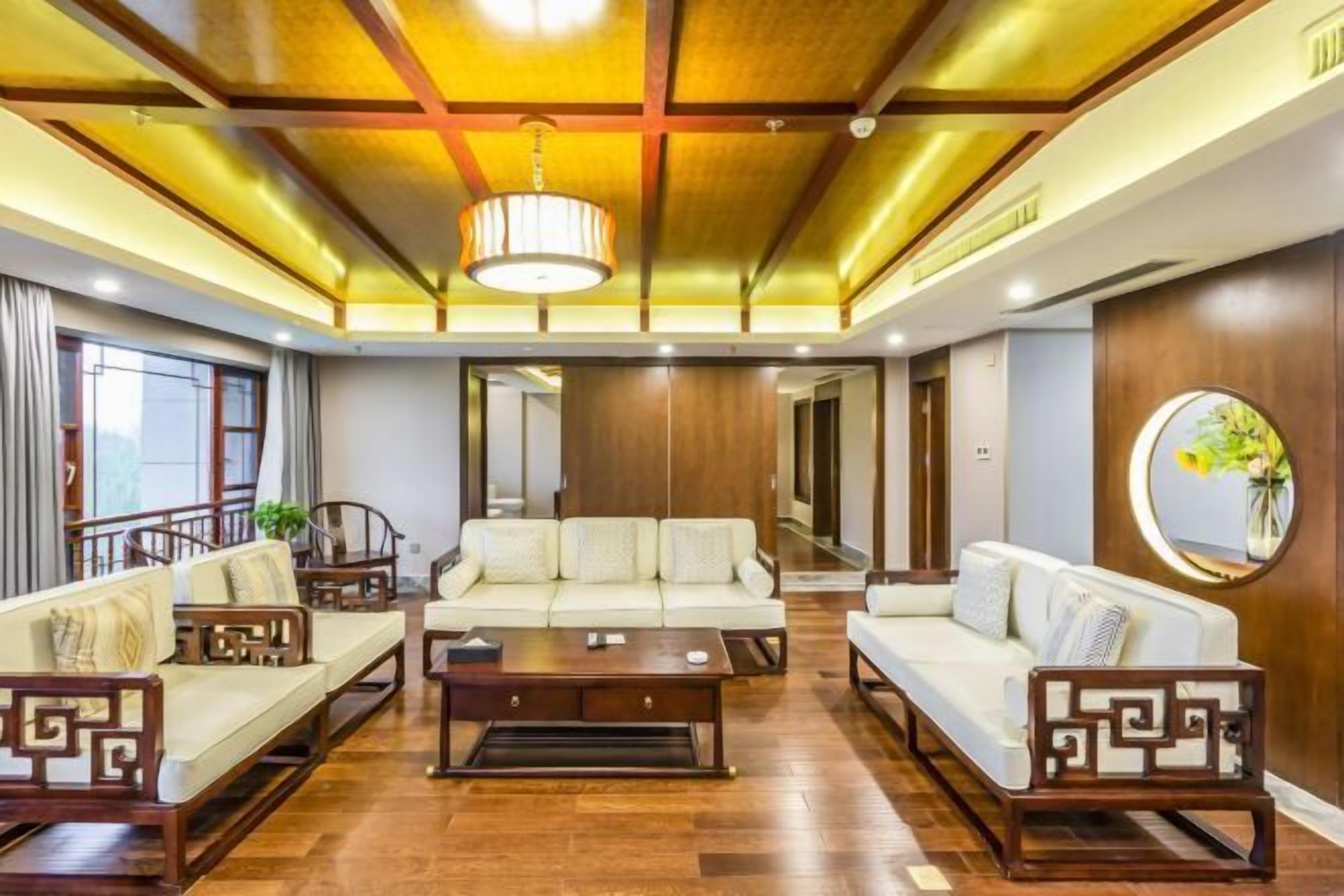 Un'ampia zona giorno con soffitto in legno, un divano, un tavolino da caffè e uno specchio decorativo.