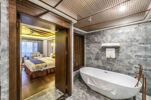 A modern bathroom with a freestanding bathtub, marble walls, and a wooden door leading to a bedroom. - Laozi Boxue International Hotel (Luyi)