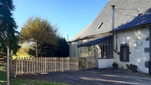 Un bâtiment blanc avec un toit en pente, une clôture en bois et une allée gravillonnée.